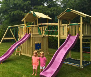 Parque infantil de madera con dos toboganes, red de escalada, puente de red y columpios en un jardín